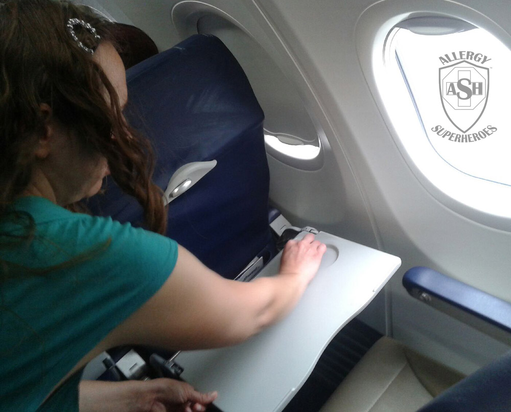 Wiping down an airplane tray table before taking a flight | Allergy Superheroes