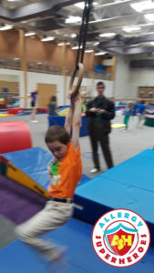 Kal swinging on the rings at a food allergy inclusive birthday party by Allergy Superheroes.