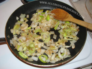 Sauteed onions in a frying pan with wooden spoon | by Food Allergy Superheroes