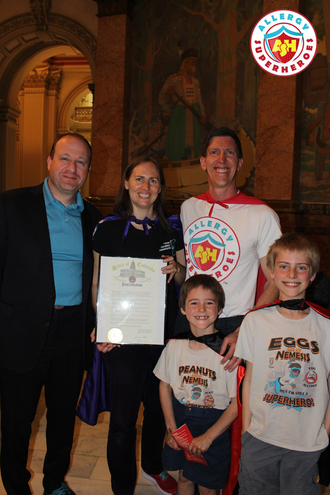 The Allergy Superheroes Family with Governor Jared Polis, holding the Food Allergy Week Proclamation | by Food Allergy Superheroes