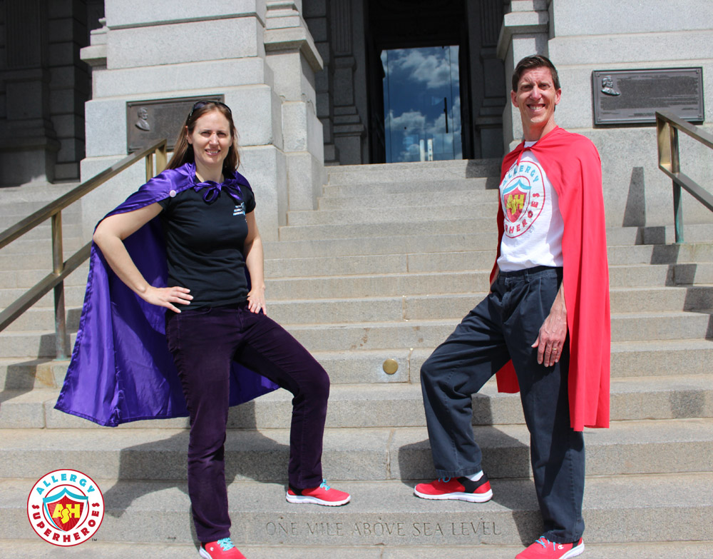 Eileen and Dean of Allergy Superheroes stand outside the Colorado State Capitol in red sneakers, Allergy Superheroes shirts, and capes | by Food Allergy Superheroes