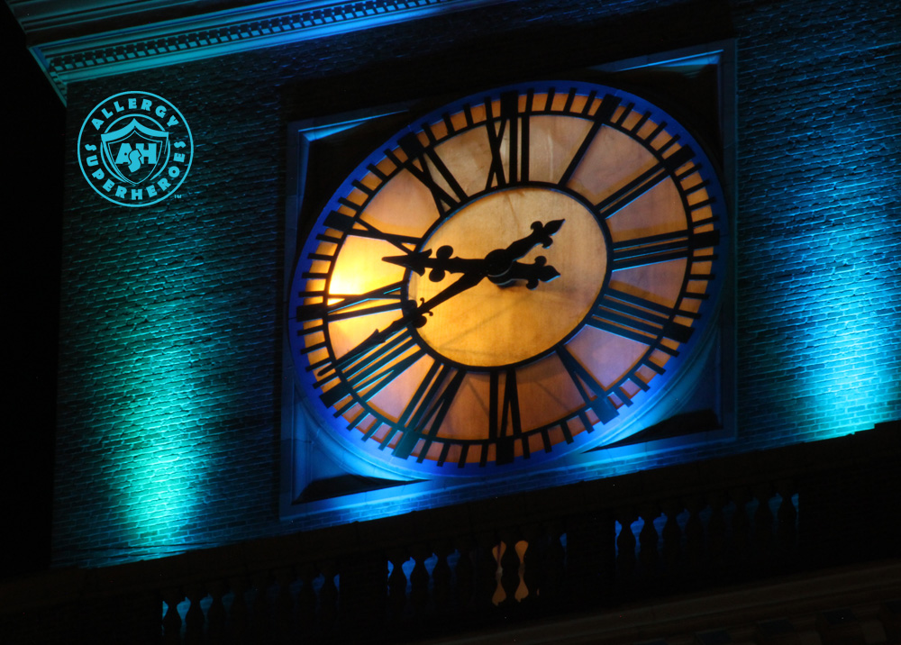 The clock face of Denver's D&F Clock Tower on 16th Street Mall, with the top floors lit up Teal for Food Allergy Awareness | by Food Allergy Superheroes